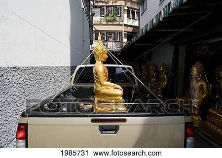 Stock Image - Thailand, Bangkok, Buddha Tied Down By It's Crown In The Bed Of A Truck.. Fotosearch