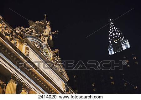 Stock Image - The top of Grand Central Station with the Chrysler Building at night; New York City, New York, United States of America. Fotosearch
