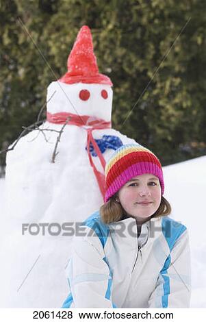 Stock Photo - Thirteen Year Old Girl Kneeling Beside Snowman, Winnipeg, Canada. Fotosearch
