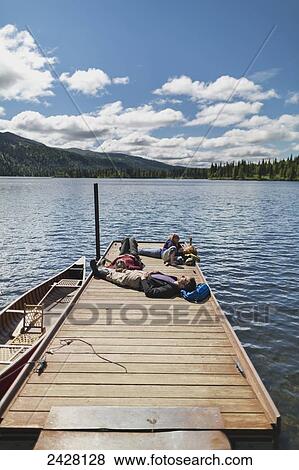 Three adults and a young girl lounging on a boat dock on a lake soaking up the sun, Byers Lake campground, Denali State Park; Alaska, United States of America View Large Photo Image Stock Photo - Three adults and a young girl lounging on a boat dock on a lake soaking up the sun, Byers Lake campground, Denali State Park; Alaska, United States of America. Fotosearch