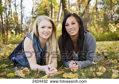 Stock Image - Two girlfriends spending time together in a park; Edmonton, Alberta, Canada. Fotosearch