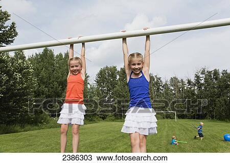 Two girls holding onto the crossbar of a soccer goal post in a park; Stony Plain, Alberta, Canada View Large Photo Image Stock Image - Two girls holding onto the crossbar of a soccer goal post in a park; Stony Plain, Alberta, Canada. Fotosearch