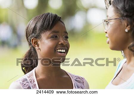 Stock Photo - Two sisters spending quality time together in a park; Edmonton, Alberta, Canada. Fotosearch
