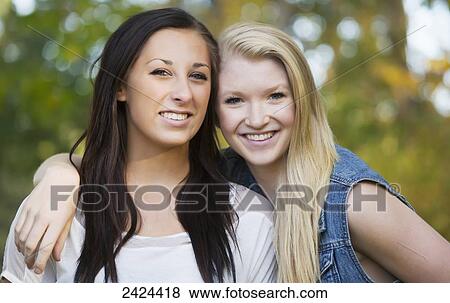 Stock Photo - Two teenage girls posing together in a park in autumn; Edmonton, Alberta, Canada. Fotosearch