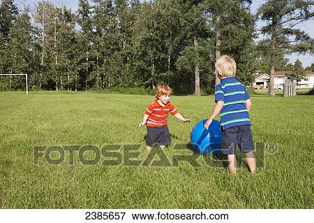Two young boys play with a large ball on a grass field; Stony Plain, Alberta, Canada View Large Photo Image Stock Photo - Two young boys play with a large ball on a grass field; Stony Plain, Alberta, Canada. Fotosearch