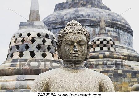 Uncovered Buddha statue amidst the latticed stone stupas containing Buddha statues on the upper terrace, Borobudur Temple Compounds, Central Java, Indonesia View Large Photo Image Picture - Uncovered Buddha statue amidst the latticed stone stupas containing Buddha statues on the upper terrace, Borobudur Temple Compounds, Central Java, Indonesia. Fotosearch