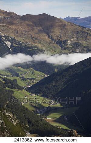 View from a mountain top looking down a green meadow valley with some cloud cover settled in the valley and mountain range in the distance; Hintertux, Austria View Large Photo Image Stock Image - View from a mountain top looking down a green meadow valley with some cloud cover settled in the valley and mountain range in the distance; Hintertux, Austria. Fotosearch