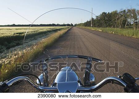 Stock Image - View of a dirt road through a motorcycle windshield; Winnipeg, Manitoba, Canada. Fotosearch