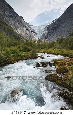 Water rushing in a river in a valley of trees between the mountains; Olden, Norway View Large Photo Image Stock Photo - Water rushing in a river in a valley of trees between the mountains; Olden, Norway. Fotosearch