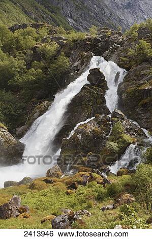 Waterfall rushing over rocks and splashing into a river; Olden, Norway View Large Photo Image Stock Photograph - Waterfall rushing over rocks and splashing into a river; Olden, Norway. Fotosearch