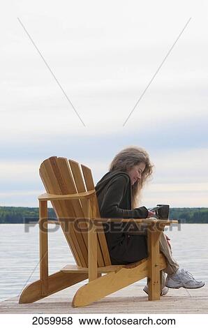 Woman Dialing On Cellphone, Seated In Deck Chair On Dock, Clear Lake, Manitoba, Canada View Large Photo Image Stock Photo - Woman Dialing On Cellphone, Seated In Deck Chair On Dock, Clear Lake, Manitoba, Canada. Fotosearch