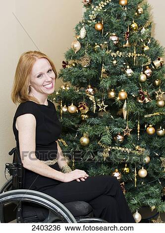 Stock Photograph - Woman in a wheelchair beside a Christmas tree; Edmonton, Alberta, Canada. Fotosearch