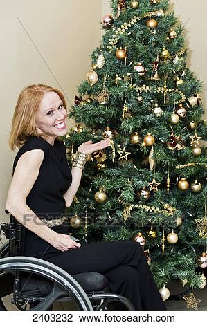 Stock Image - Woman in a wheelchair decorating a Christmas tree; Edmonton, Alberta, Canada. Fotosearch