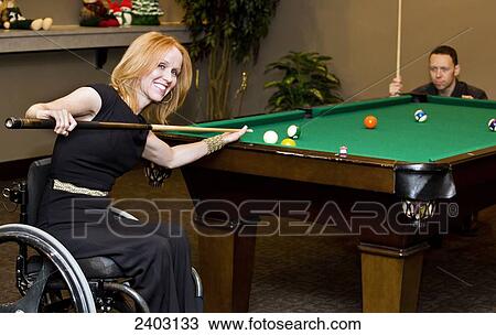 Stock Image - Woman in a wheelchair playing pool with her husband; Edmonton, Alberta, Canada. Fotosearch