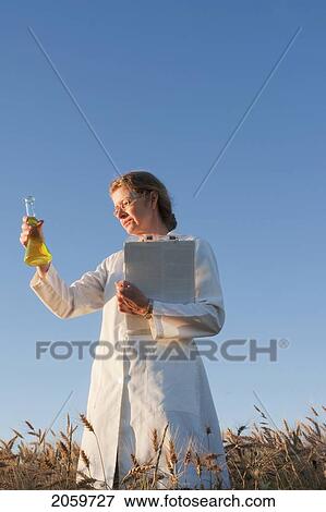 Stock Photo - Woman In Field Of Wheat Holds Clipboard And Flask, Manitoba, Canada. Fotosearch
