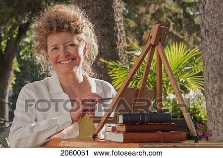 Woman In Mid 50's Seated Outdoor With Small Painting Easel, Manitoba, Canada View Large Photo Image Stock Image - Woman In Mid 50's Seated Outdoor With Small Painting Easel, Manitoba, Canada. Fotosearch