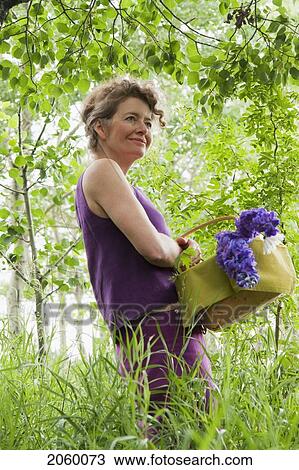 Woman In Mid-50's With Basket Of Flowers In Grove Of Trees, Manitoba Canada View Large Photo Image Stock Image - Woman In Mid-50's With Basket Of Flowers In Grove Of Trees, Manitoba Canada. Fotosearch
