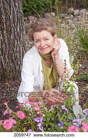 Woman Kneeling Beside Flowers In Garden, Manitoba, Canada View Large Photo Image Stock Photo - Woman Kneeling Beside Flowers In Garden, Manitoba, Canada. Fotosearch