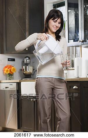 Stock Photo - Woman Pours Glass Of Water From Filtre Jug, Winnipeg, Canada. Fotosearch