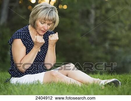 Stock Image - Woman praying in a park; Edmonton, Alberta, Canada. Fotosearch
