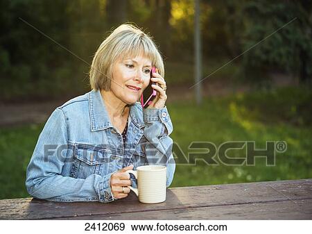 Woman using a cell phone in a park; Edmonton, Alberta, Canada View Large Photo Image Stock Photo - Woman using a cell phone in a park; Edmonton, Alberta, Canada. Fotosearch