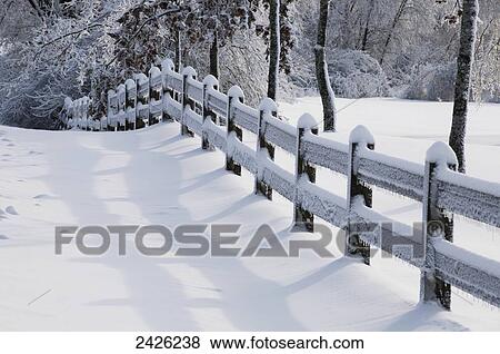 Stock Photo - Wooden fence covered in snow and ice after a freezing rain storm; West Bolton, Quebec, Canada. Fotosearch