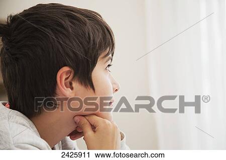 Stock Image - Young boy in contemplative mood looking out the window; Langley, British Columbia, Canada. Fotosearch