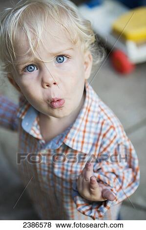 Stock Photo - Young boy looks quizzically up at the camera; Toronto, Ontario, Canada. Fotosearch