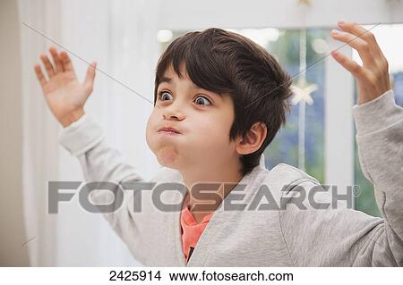 Picture - Young boy making a silly face near a window in a bedroom; Langley, British Columbia, Canada. Fotosearch