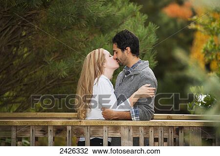 Young couple kissing on a bridge in a park; Langley, British Columbia, Canada View Large Photo Image Stock Image - Young couple kissing on a bridge in a park; Langley, British Columbia, Canada. Fotosearch