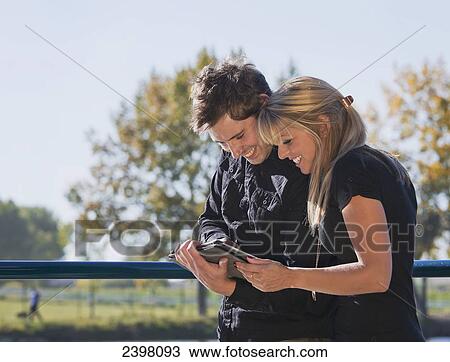 Young couple looking at pictures on tablet; Edmonton, Alberta, Canada View Large Photo Image Stock Image - Young couple looking at pictures on tablet; Edmonton, Alberta, Canada. Fotosearch