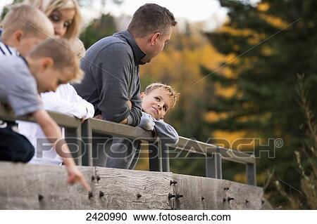 Stock Image - Young family on a bridge in a park in autumn; Edmonton, Alberta, Canada. Fotosearch