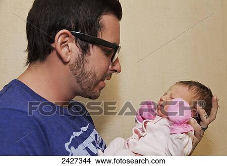 Young father holding his newborn daughter in a maternity ward; Edmonton, Alberta, Canada View Large Photo Image Picture - Young father holding his newborn daughter in a maternity ward; Edmonton, Alberta, Canada. Fotosearch
