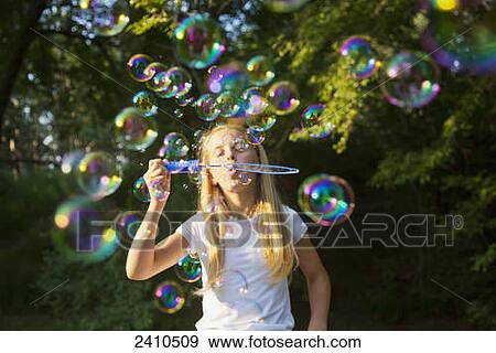 Young girl blowing bubbles in a park; St. Albert, Alberta, Canada View Large Photo Image Stock Photo - Young girl blowing bubbles in a park; St. Albert, Alberta, Canada. Fotosearch