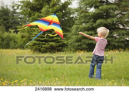 Stock Photo - Young girl flying a kite in a field of wildflowers; Thunder Bay, Ontario, Canada. Fotosearch