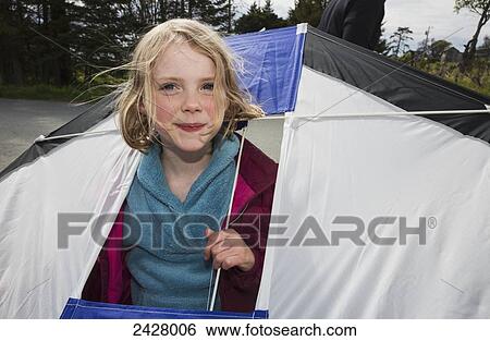 Stock Photograph - Young girl holding a kite with her head poking through an opening in the kite, Bishops Beach, Katchemak Bay; Homer, Alaska, United States of America. Fotosearch
