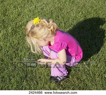 Young girl looking through a magnifying glass in a park; St. Albert, Alberta, Canada View Large Photo Image Stock Photograph - Young girl looking through a magnifying glass in a park; St. Albert, Alberta, Canada. Fotosearch