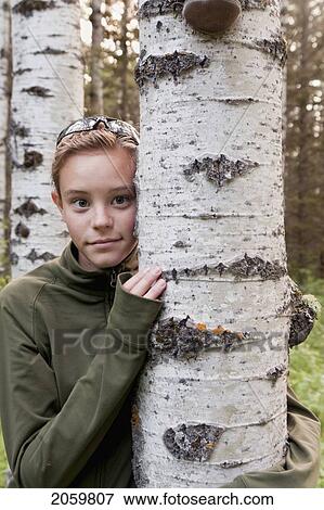 Stock Photo - Young Girl With Arm Around Tree, Manitoba, Canada. Fotosearch