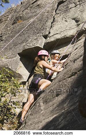 Stock Photograph - Young Woman Climbing With Daughter (Age 7) Up Granite Cliff At Stone Hills Near Rexford, Montana, Usa. Fotosearch
