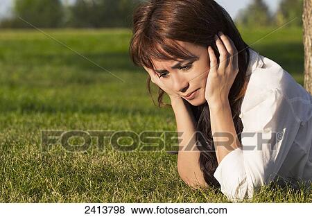 Stock Photo - Young woman feeling heavy hearted in a park; Edmonton, Alberta, Canada. Fotosearch
