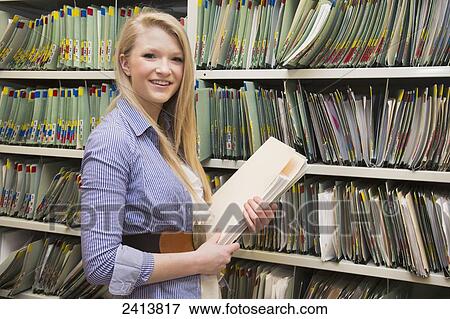 Young woman filing documents at an accounting office; Edmonton, Alberta, Canada View Large Photo Image Stock Photo - Young woman filing documents at an accounting office; Edmonton, Alberta, Canada. Fotosearch