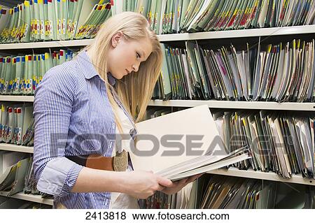 Young woman filing documents at an accounting office; Edmonton, Alberta, Canada View Large Photo Image Stock Photo - Young woman filing documents at an accounting office; Edmonton, Alberta, Canada. Fotosearch