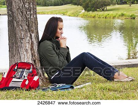 Stock Photo - Young woman praying outdoors in a park; St. Albert, Alberta, Canada. Fotosearch
