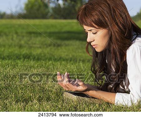 Young woman praying with her Bible in a park; Edmonton, Alberta, Canada View Large Photo Image Picture - Young woman praying with her Bible in a park; Edmonton, Alberta, Canada. Fotosearch