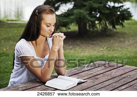 Young woman reading her Bible and praying outdoors in a park; St. Albert, Alberta, Canada View Large Photo Image Stock Photo - Young woman reading her Bible and praying outdoors in a park; St. Albert, Alberta, Canada. Fotosearch