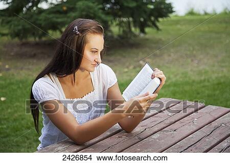 Picture - Young woman reading her Bible outdoors in a park; St. Albert, Alberta, Canada. Fotosearch