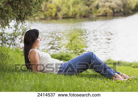 Young woman relaxing on the shore of a lake; Edmonton, Alberta, Canada View Large Photo Image Stock Photo - Young woman relaxing on the shore of a lake; Edmonton, Alberta, Canada. Fotosearch