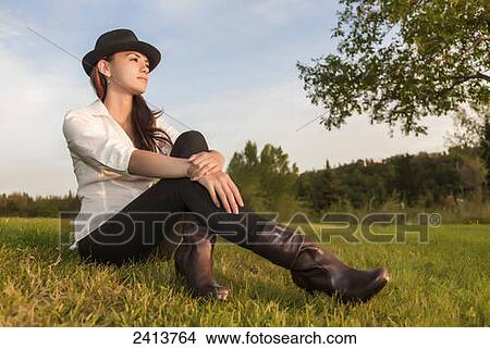 Young woman sitting on the grass in a park; Edmonton, Alberta, Canada View Large Photo Image Picture - Young woman sitting on the grass in a park; Edmonton, Alberta, Canada. Fotosearch