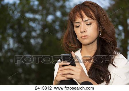 Young woman using a cell phone in a park; Edmonton, Alberta, Canada View Large Photo Image Stock Image - Young woman using a cell phone in a park; Edmonton, Alberta, Canada. Fotosearch