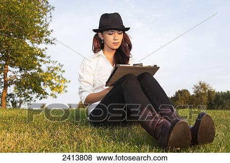 Young woman using her tablet in a park; Edmonton, Alberta, Canada View Large Photo Image Stock Photo - Young woman using her tablet in a park; Edmonton, Alberta, Canada. Fotosearch